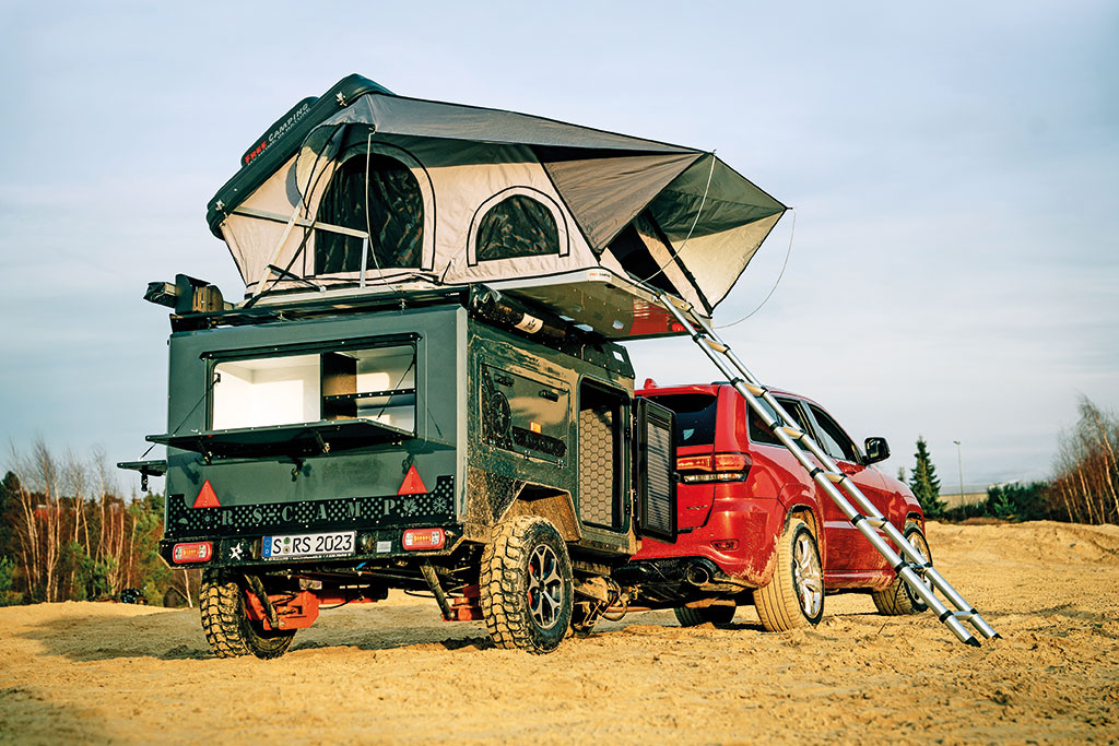 Kompakte Mini-Wohnwagen: Rotes Auto mit angehängtem kleinen Wohnwagen von RS-Camp mit Dachzelt