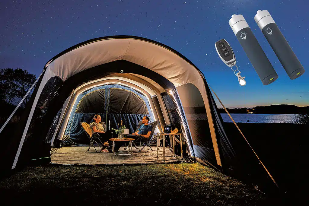 Stimmungsvoll beleuchtetes kuppelförmiges Vorzelt mit nach vorne offener Seite bei Nacht, im Zelt sitzen eine Frau und ein Mann auf Campingstühlen